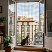 Gato doméstico mirando de forma segura a través de un balcón protegido con una red de seguridad para mascotas de alta resistencia